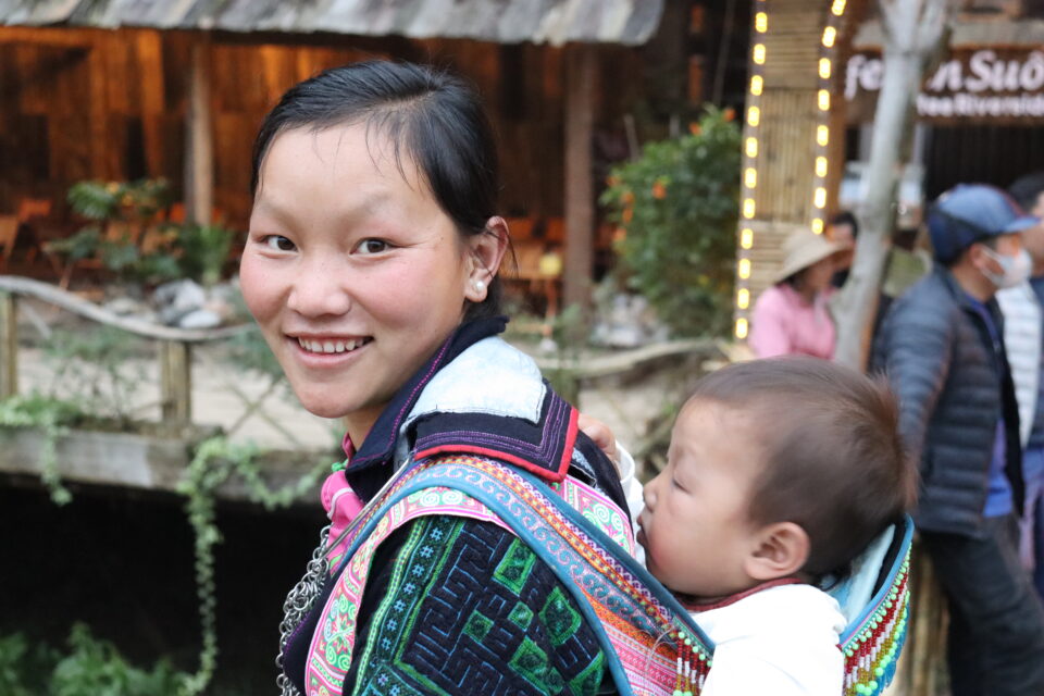 Ragazza Hmong con la sua bambina avvolta in una sacca sulla schiena 