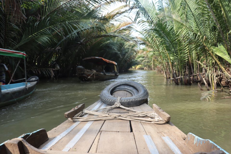 Canoa di legno che galleggia sul verde fiume Mekong, in mezzo alla natura al Sud del Vietnam. 